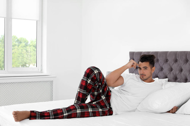 Fiatal férfi feküdt ágyban, puha párnák között otthon - Fotó, kép