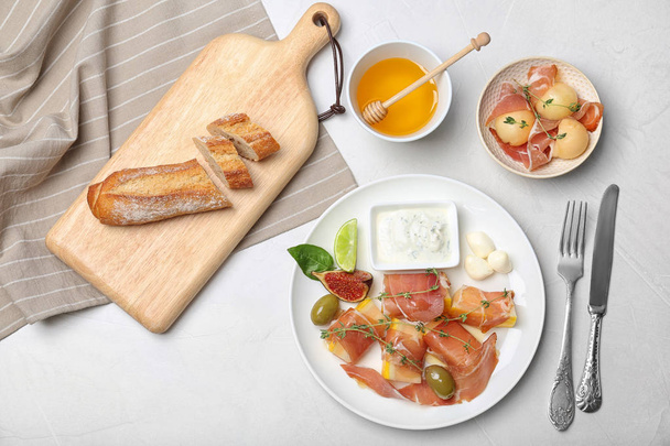 Flat lay composition with melon and prosciutto appetizer on light table - Photo, Image