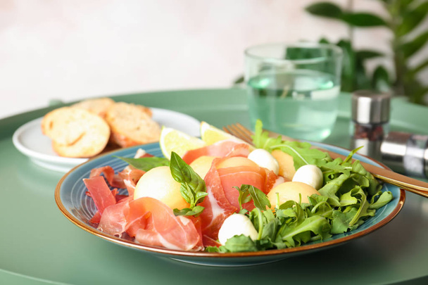 Plate with melon balls, mozzarella and prosciutto on table - Foto, Bild