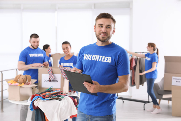 Male volunteer with clipboard listing donations indoors - Фото, зображення
