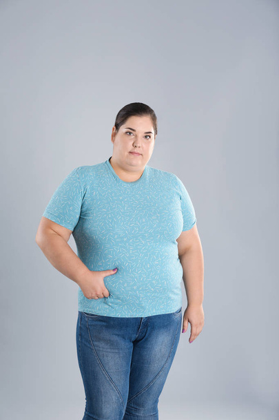 Übergewichtige Frau berührt Bauchfett vor Gewichtsverlust auf farbigem Hintergrund - Foto, Bild
