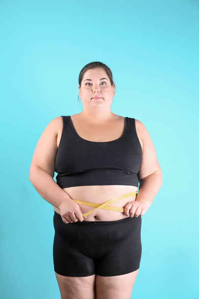 Overweight woman measuring waist before weight loss on color background - Fotoğraf, Görsel