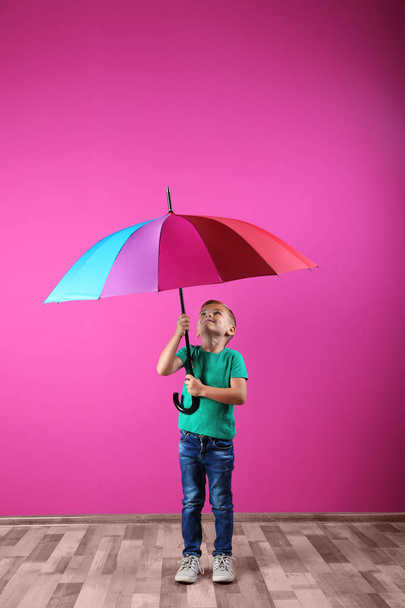 Little boy with rainbow umbrella near color wall - Fotó, kép