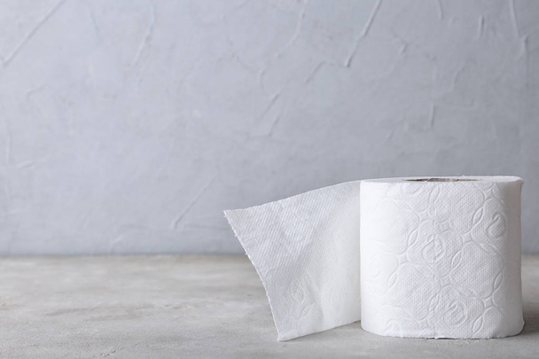 Roll of toilet paper on grey table. Space for text - Foto, imagen