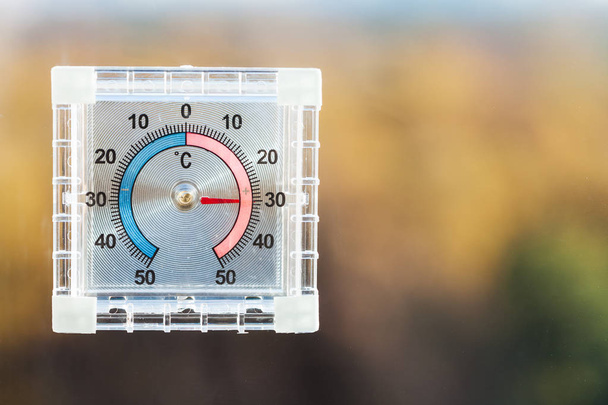 standpunt van buiten thermometer home venster en wazig herfst bos in warme dag - Foto, afbeelding
