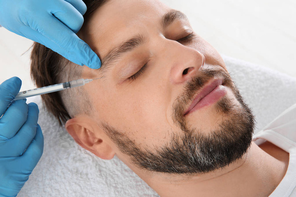 Man getting facial injection in clinic. Cosmetic surgery concept - Photo, image