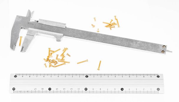 old steel calipers, metallic ruler and many of brass screws on white background - Photo, Image