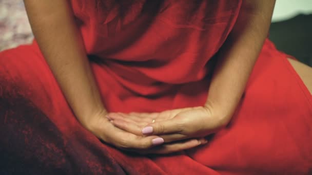 Femme en robe rouge méditant assise les mains croisées à l'intérieur, les yeux fermés
 - Séquence, vidéo