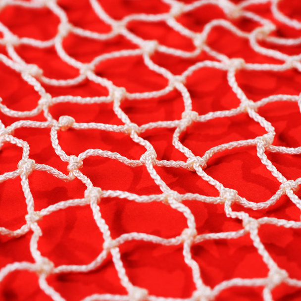 weißes Fischernetz vor rotem Hintergrund. Textur der Fischernetze - Foto, Bild