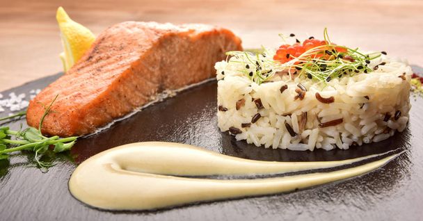 white rice red fish with sauce on a black wooden tray - Foto, Bild