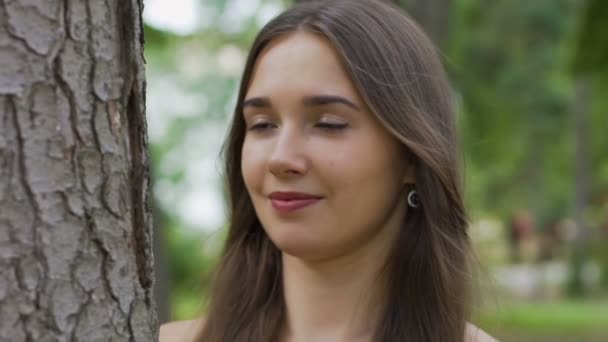 Beautiful brunette looks and hugs tree, feels love and unity with nature oneness - Záběry, video