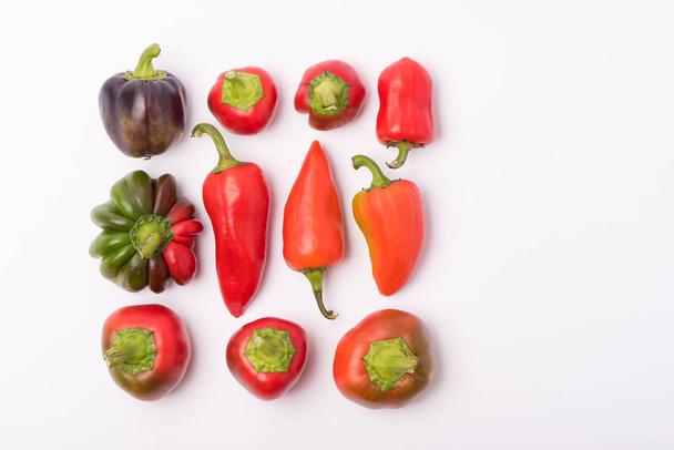 Several beautiful ripe sweet and hot peppers of red and orange on a white background - Photo, Image