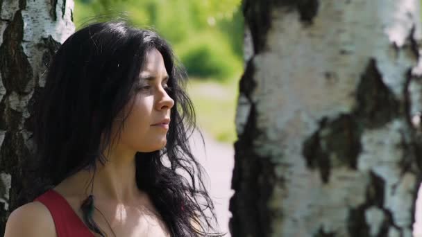 Woman in park looks up to sun closing eyes, beautiful female dark hair outdoors - Filmagem, Vídeo