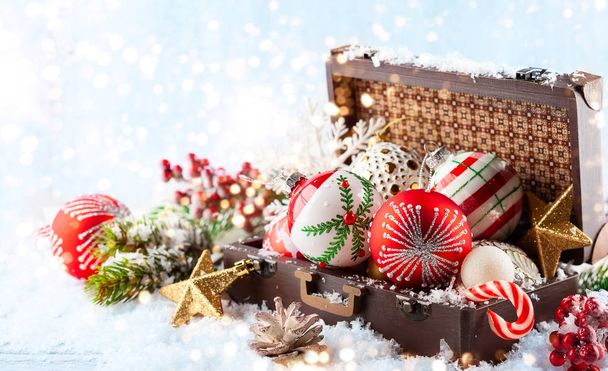 Maleta vintage con decoraciones navideñas festivas para el árbol de Navidad en la nieve
 - Foto, Imagen