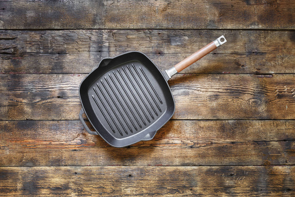 Cast iron frying pan grilling on a wooden table, top view - Photo, Image