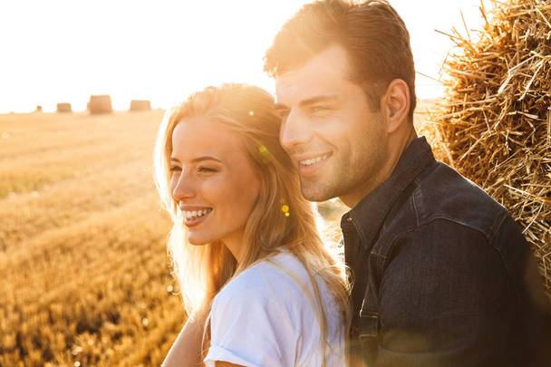 Image of amazing happy young loving couple standing on the field posing. - Foto, imagen