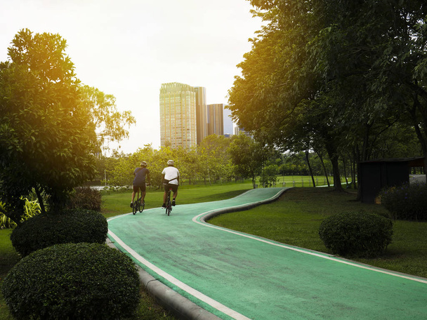 Twee mannen zijn fietsen op een fietspad in een openbaar park. - Foto, afbeelding