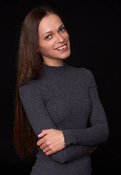 Beautiful woman with long brown hair. Portrait of a pretty smiling girl over black studio background - Zdjęcie, obraz