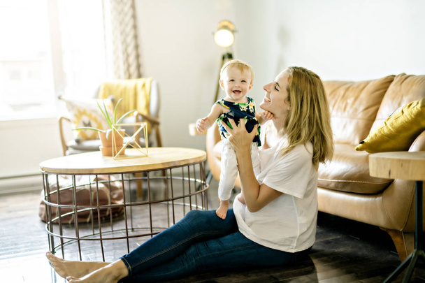 happy family. Mother and baby daughter plays, on the livingroom - 写真・画像