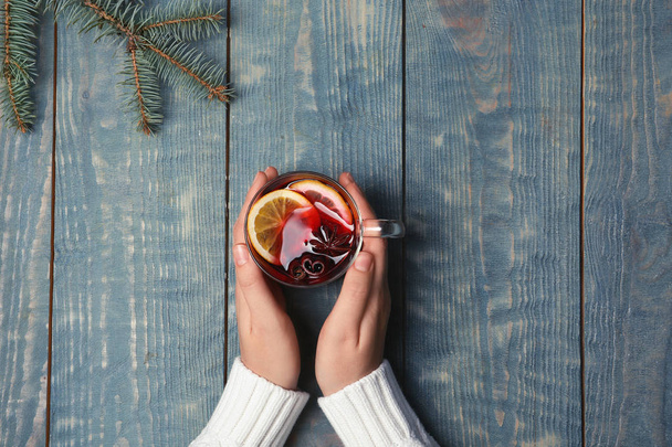 Woman holding cup with hot mulled wine on table, top view - Photo, Image
