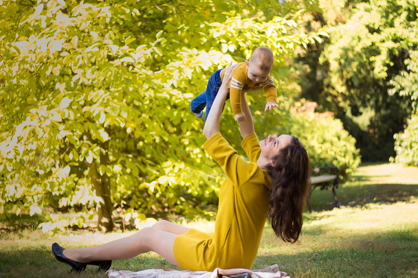 Jovem mãe feliz brincando com o bebê no parque de outono com folhas de bordo amarelas.Família andando ao ar livre no outono. Menino com sua mãe brincando no parque no outono
. - Foto, Imagem