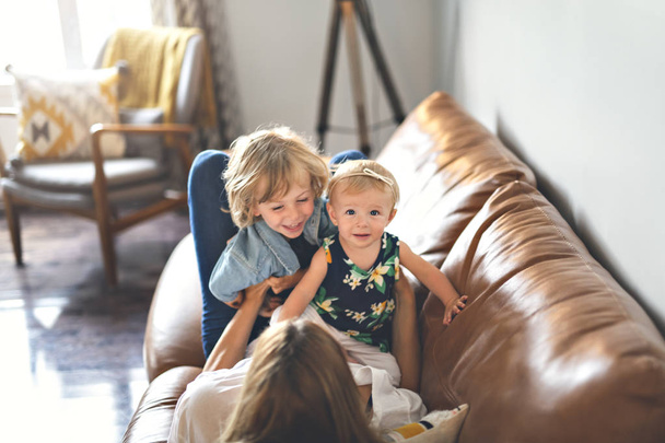 Young father with baby daughter and son on sofa at home - Photo, Image