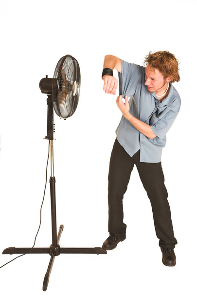 Man with blue shirt cooling down in front of a fan. - Фото, зображення