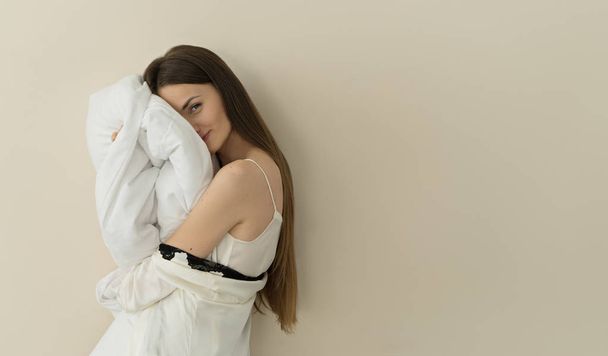 portrait of young brunette woman holding pillow by head - Foto, Imagem
