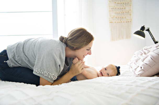 A Mother and baby girl on a white bed - Foto, afbeelding
