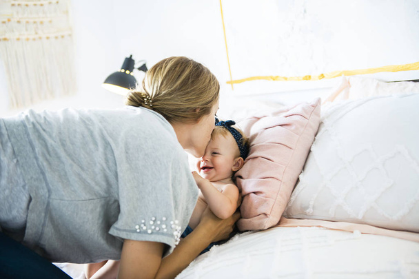 Mother and baby girl on a white bed - Foto, imagen