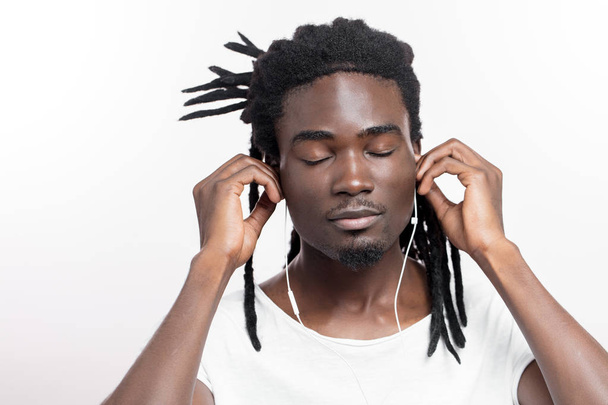 dark skinned man with dreadlocks listening music on headphones - Fotó, kép