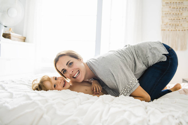Young mother with her little son relaxing and playing in the bed at the weekend together - Foto, Imagem