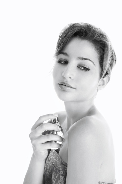Black and white view of a young woman spraying perfume on her bare shoulders - Photo, Image