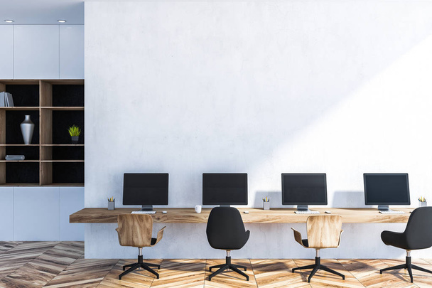 Büroinnenraum mit weißen Wänden und Holzboden, langer Holztisch mit vier Computerbildschirmen. Bücherregal im Hintergrund. 3D-Rendering Kopierraum - Foto, Bild