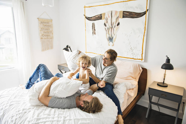 Family with child having fun on bed with pillow fight - Fotografie, Obrázek