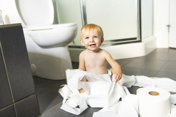 Niño rompiendo papel higiénico en el baño - Foto, imagen
