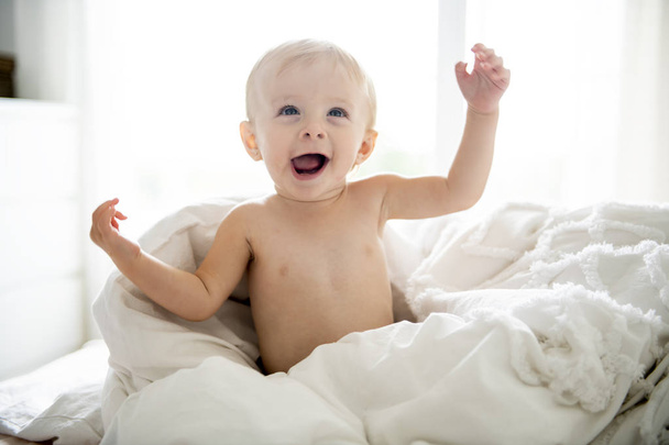 Cute 8 months baby girl on bed on the morning - 写真・画像