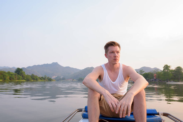 Τουριστική άνθρωπος που κάθεται στο σκάφος ενώ έχοντας διακοπών στην Ταϊλάνδη - Φωτογραφία, εικόνα