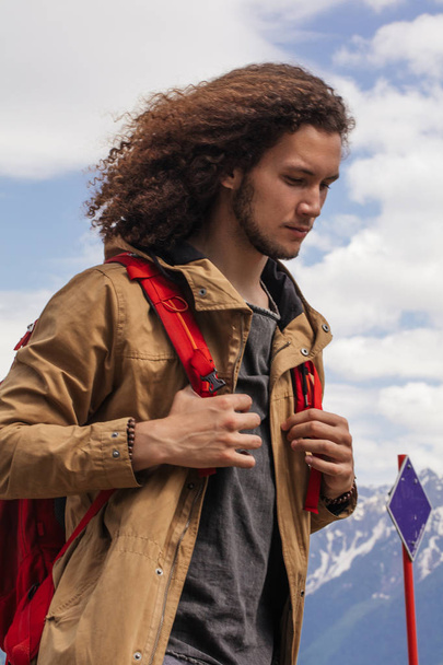 Voyageur homme avec sac à dos rouge relaxant en plein air avec des montagnes rocheuses sur fond - Photo, image