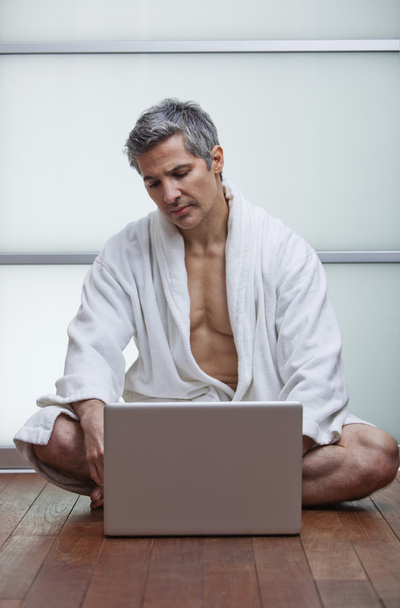 άνθρωπος φορώντας μπουρνούζι και χρησιμοποιώντας ένα φορητό υπολογιστή - Φωτογραφία, εικόνα