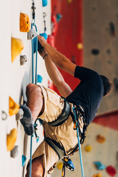 Homem alpinista na parede de escalada artificial em bouldering ginásio
 - Foto, Imagem