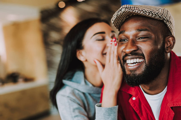 Excited man smiling and his girlfriend telling him her secret - Photo, Image
