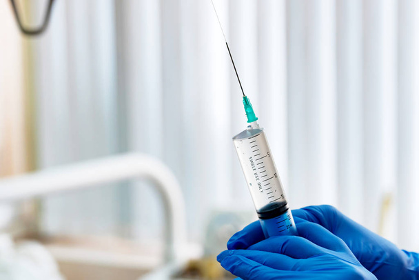 Hands in gloves hold syringe with injection - Photo, image