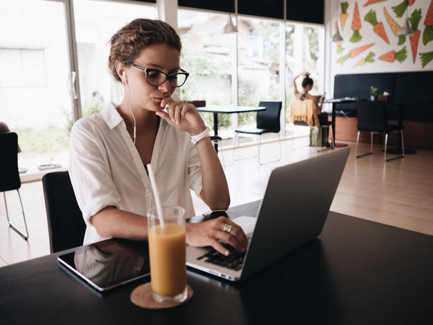 junge Studentin mit Laptop sitzt im Café und arbeitet mit Laptop beim Frühstück - Foto, Bild