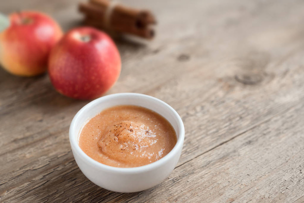 Apple sauce. Fresh homemade applesauce (apple puree, mousse, sauce) with cinnamon and apples on wooden table, copy space - 写真・画像