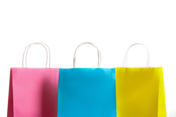 Many blank paper shopping bags of different colors, pink, blue and yellow isolated on white background. Blank colorful packets. Black friday sale concept. Close up copy space. - 写真・画像
