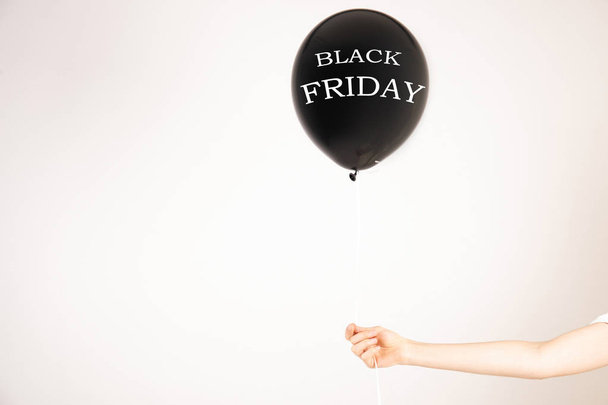 Black Friday on black balloon in girl's hand. Black friday sale concept. Fourth Friday of November, beginning of Christmas shopping season since 1952. Copy space, close up, top view, flat lay. - Фото, изображение