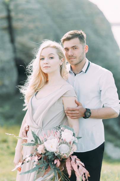 Wedding couple on a walk, photo shoot in the mountains. Fine art style in the decor. A stylish young model - Foto, immagini