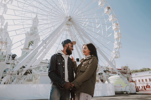Cheerful young couple standing near Ferris wheel - Foto, afbeelding