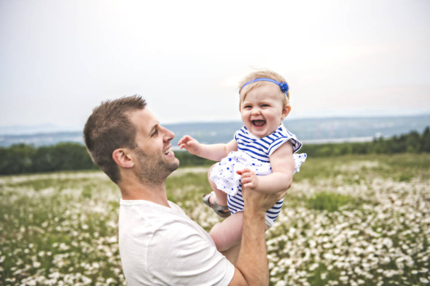 kleines Mädchen und sein Vater genießen draußen im Feld von Gänseblümchen-Blumen - Foto, Bild